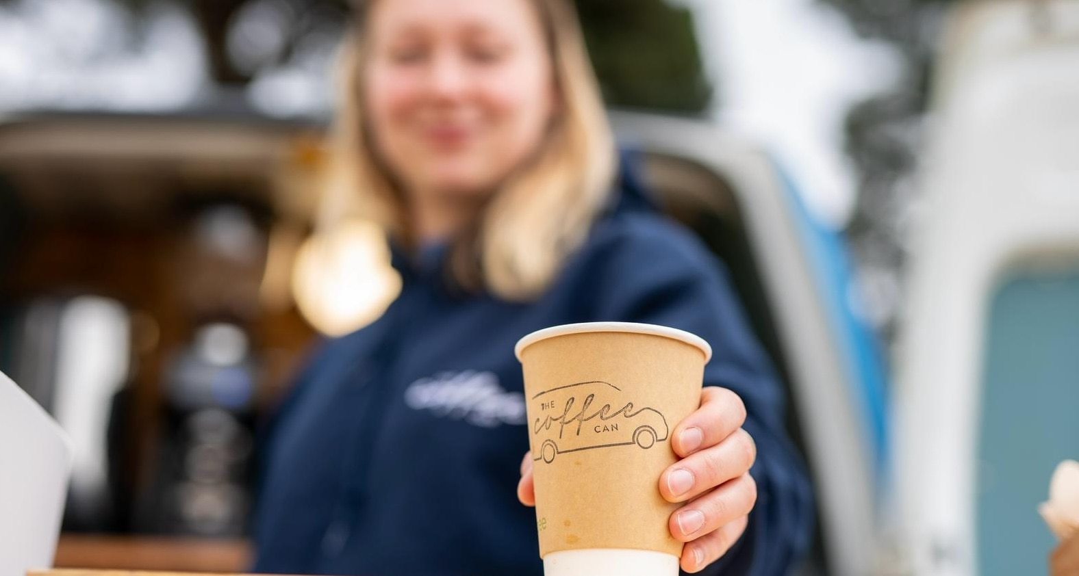 Amy serving a cup of her finest coffee from the back of her Ford van
